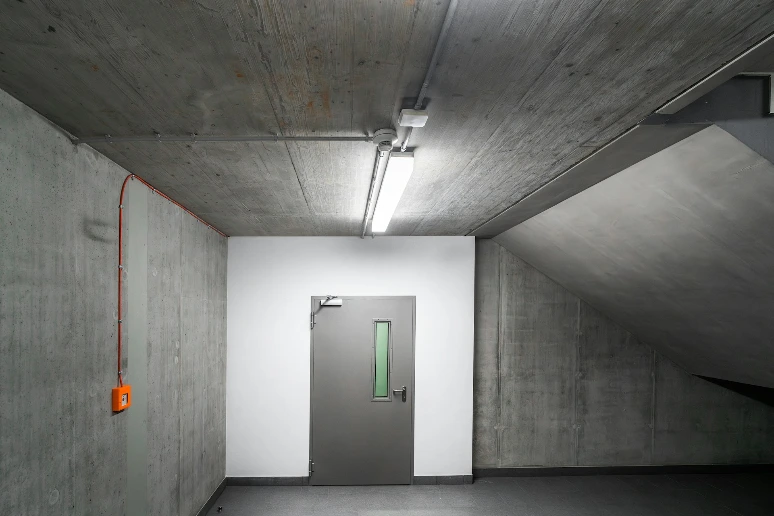 an empty room with a door and a green light